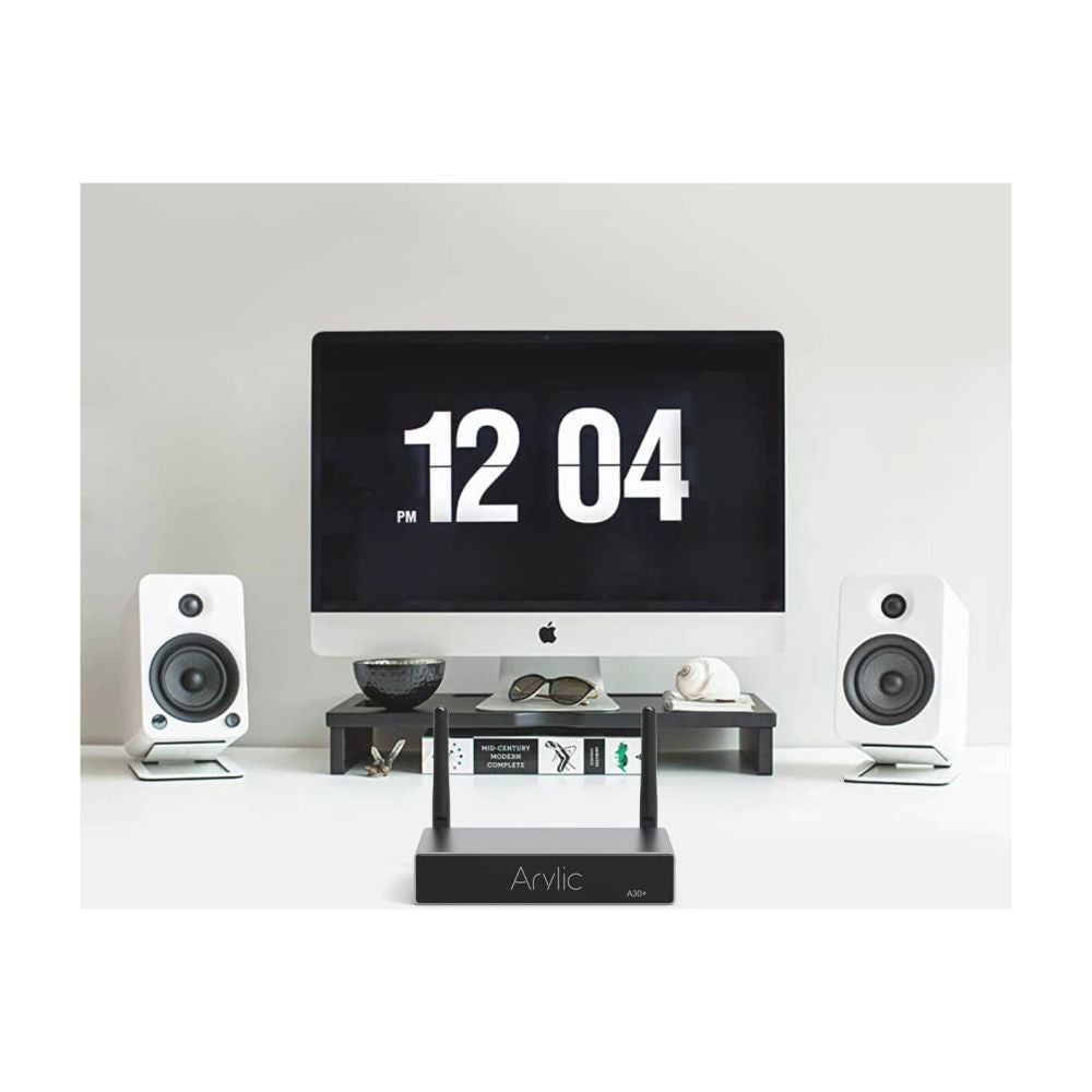 Computer monitor with digital clock display, flanked by two speakers on a white surface.